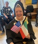 Carmelite Sister poses with flags to celebrate America and how Foundress Mother Angeline was an American immigrant from Ireland.
