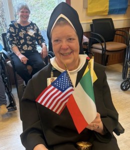 Carmelite Sister poses with flags to celebrate America and how Foundress Mother Angeline was an American immigrant from Ireland.